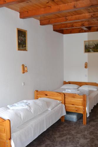 two beds in a room with white walls and wooden ceilings at Pensiunea Muntean in Sibiel