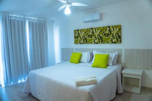 a bedroom with a large white bed with green pillows at Arraial D'Ajuda, Altos da pitinga ,3 suítes in Arraial d'Ajuda