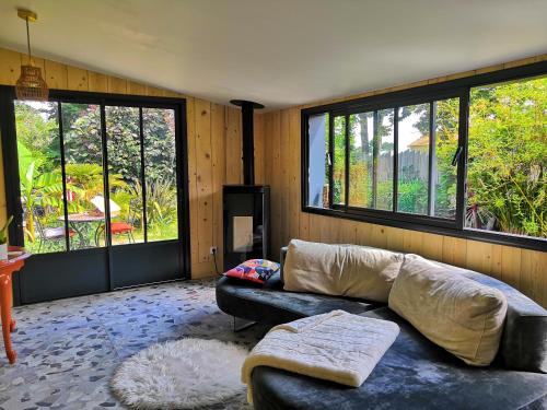 een woonkamer met een bank en een aantal ramen bij Un petit coin de paradis in Saint-Brevin-les-Pins