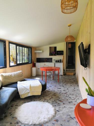 ein Wohnzimmer mit einem Sofa und einem Tisch in der Unterkunft Un petit coin de paradis in Saint-Brevin-les-Pins