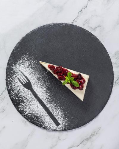 a black plate with a dessert on it with a fork at Eliza Hotel by Panel Hospitality in Nei Poroi