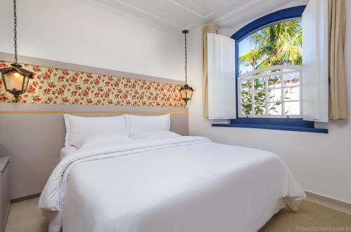 een slaapkamer met een wit bed en een raam bij Pousada Aconchego in Paraty