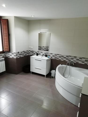 a bathroom with a tub and a sink and a mirror at BUELIÑA DA CARBALLEIRA in Teo