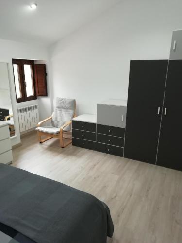 a bedroom with a bed and a dresser and a chair at BUELIÑA DA CARBALLEIRA in Teo