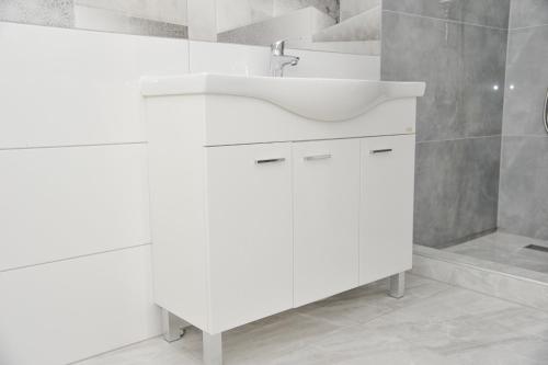 Un baño blanco con lavabo y espejo. en Villa Kalypso, en Bihać