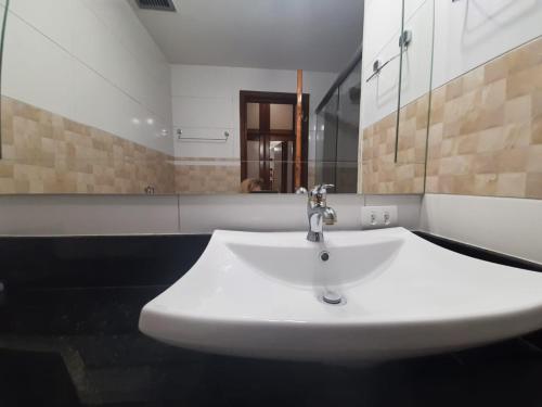 lavabo blanco en el baño con espejo en Suite Real Residencial, en Río de Janeiro