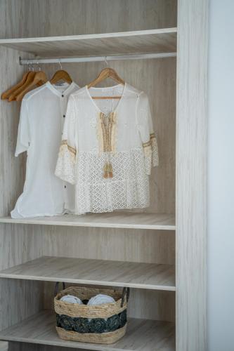 a closet with white shirts and a basket at Hostal Rosell Boutique in San Antonio