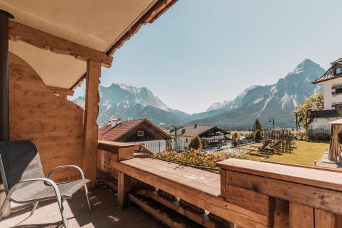 a wooden deck with a chair and a view of mountains at Alpenhof in Lermoos