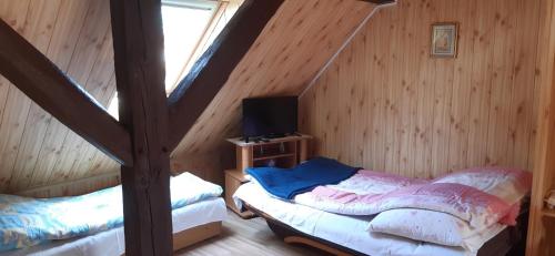 a attic room with a bed and a tv at Wczasy u Jasia in Trzęsacz