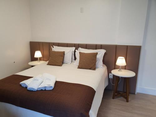 een slaapkamer met een groot bed met twee handdoeken erop bij Temporada Gramado e Canela - Apartamento Centro Campos de Canella in Canela
