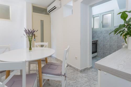 a white kitchen with a white table and chairs at Apartment Petric in Hvar