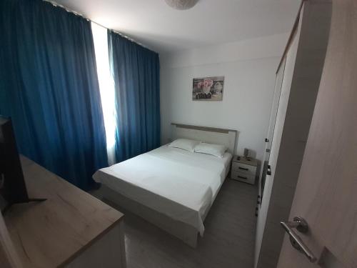 图尔恰Apartament Gabi的卧室配有白色的床和蓝色窗帘