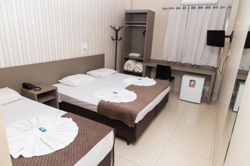um quarto de hotel com duas camas e uma televisão em Hotel Astória Maringá em Maringá