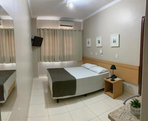 sypialnia z łóżkiem i telewizorem w obiekcie Hotel Astória Maringá w mieście Maringá