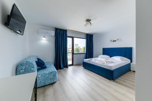 a bedroom with a bed and a tv and a chair at Vila Kos in Mamaia Nord