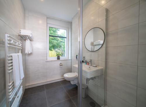 ein Badezimmer mit einem WC, einem Waschbecken und einem Spiegel in der Unterkunft Emily Hotel Leipzig Neue Messe in Leipzig
