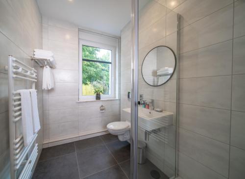 a bathroom with a toilet and a sink and a mirror at Emily Hotel Leipzig Neue Messe in Leipzig