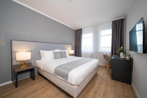 ライプツィヒにあるEmily Hotel Leipzig Neue Messeの大きなベッドとデスクが備わるホテルルームです。