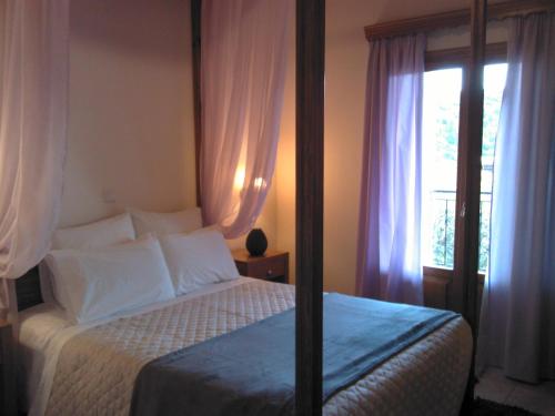 a bedroom with a bed with white sheets and a window at Menta( Archontiko Machalioti ) in Karpenision