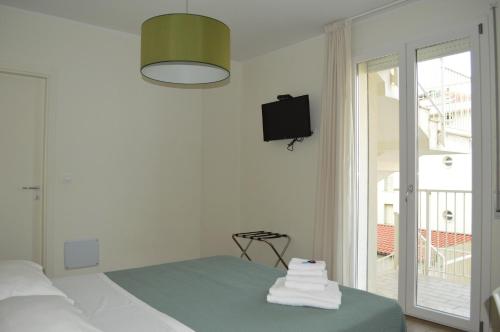 a white room with a bed and a tv on the wall at Hotel Riva e Mare in Rimini