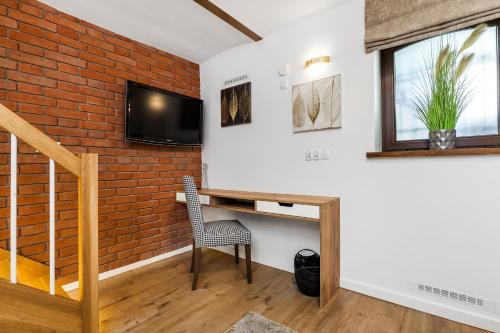 a room with a brick wall and a desk with a tv at Apartamenty4you - Apartamenty Atlantic in Sopot