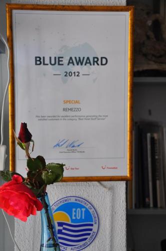 a red flower in a glass vase with a blue award sign at Remezzo Hotel & Studios in Pythagoreio
