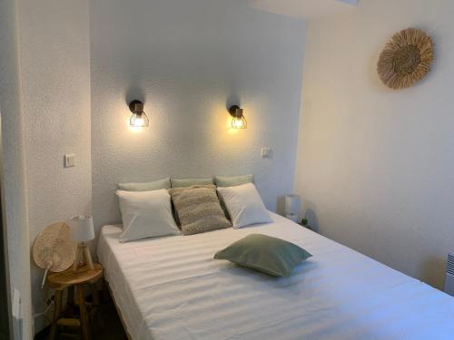 une chambre avec un grand lit blanc avec deux oreillers dans l'établissement L'émeraude avec piscine et plage, à Fouesnant