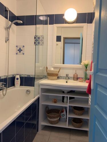 une salle de bain avec un lavabo, une baignoire et un miroir dans l'établissement L'émeraude avec piscine et plage, à Fouesnant