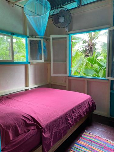 a bedroom with a pink bed and two windows at Hidden Jungle Beach House in Puerto Viejo