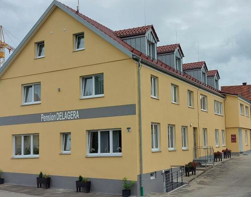 a yellow building with a sign on the side of it at Pension DELAGERA in Großmehring