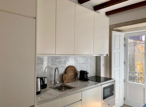 a kitchen with white cabinets and a sink at Oporto Chic&Cozy - São Bento da Vitória in Porto