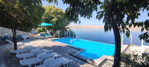 a swimming pool with white chairs next to the water at Ferienhaus ToMa in Cesarica