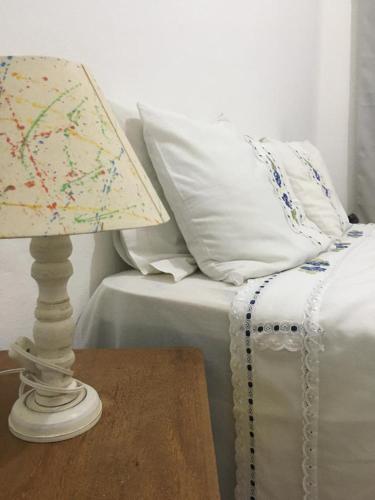 una lámpara en una mesa junto a una cama con almohadas en Cantinho de Tiradentes, en Tiradentes