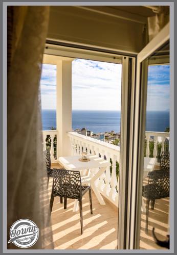 a balcony with a table and chairs and the ocean at Dorvin Apartments in Dhërmi