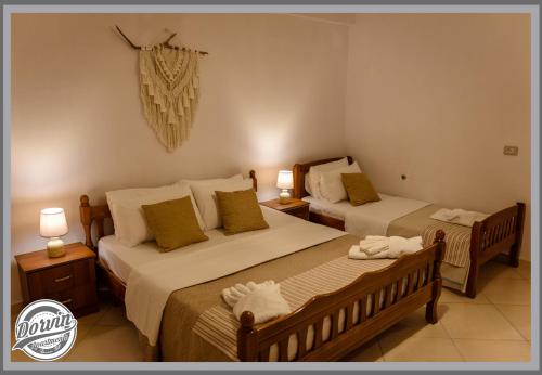 two beds in a room with two lamps and two beds at Dorvin Apartments in Dhërmi