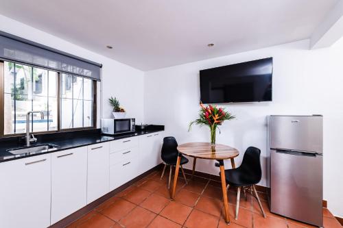 a kitchen with white cabinets and a table with flowers on it at Hotel Gardenia Tamarindo in Tamarindo