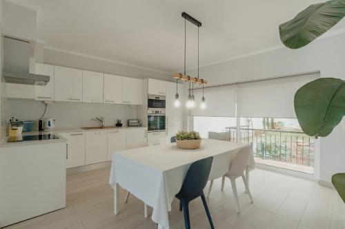 een witte keuken met een witte tafel en stoelen bij 20 da Vila - Apartment With Mezzanine With Panoramic Terrace in São Bartolomeu de Messines