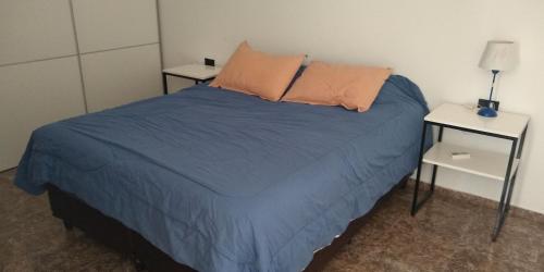 1 dormitorio con 1 cama con manta azul y 2 mesas en Amplio departamento Barrio Jardin en Córdoba