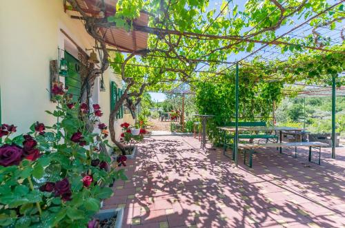 a patio with flowers and tables and benches at House Green Paradise in Vrpolje