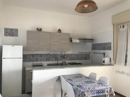a white kitchen with a table and a refrigerator at Charming Apartment in Sciacca with Sea View in Sciacca