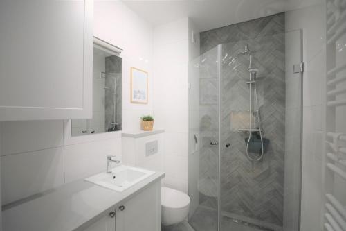 a white bathroom with a shower and a sink at HoliApart in Nautikka Park in Krynica Morska