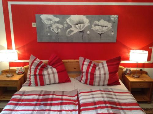 ein Schlafzimmer mit einer roten Wand und einem Bett mit Kissen in der Unterkunft Ferienwohnungen Krakolinig in Pörtschach am Wörthersee