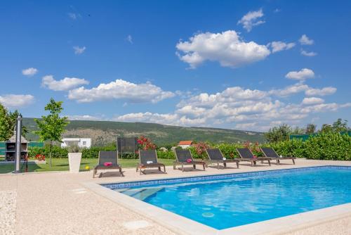 a swimming pool with lounge chairs next to at Holiday house Anetta with 5 bedrooms in Imotski