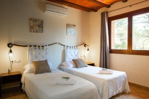 a bedroom with two beds with white sheets and a window at AldeaMia, Cozy villa for 8 people, pool, mountain view, beach at 8 min in Vilanova de Escornalbou