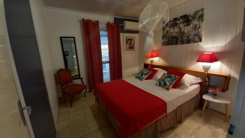 a bedroom with a bed with a red blanket at Les Gites Capra - Papaye in Bouillante