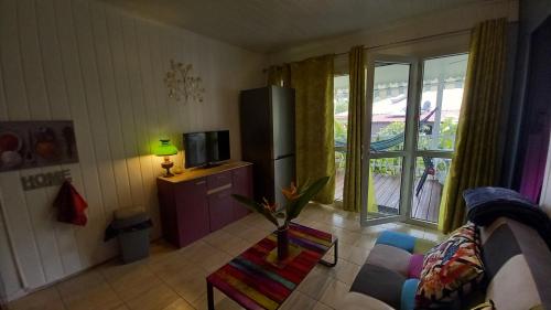 a living room with a couch and a tv and a window at Les Gites Capra - Papaye in Bouillante
