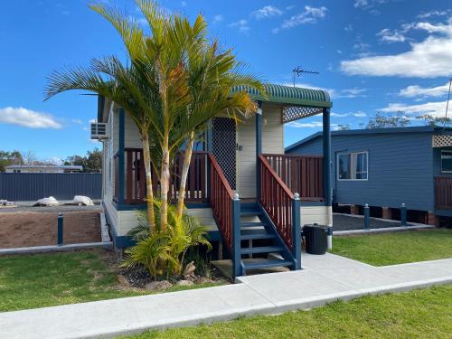 a house with a staircase and a palm tree at Amaroo Resort in Sussex inlet