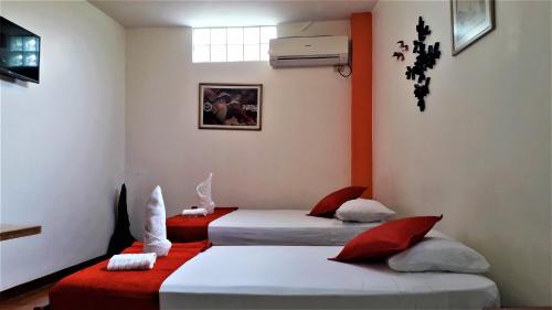 two beds in a room with red and white at Hostal El Pinzón in Puerto Ayora