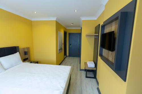 a bedroom with a bed and a tv and yellow walls at Roy Otel Akçay in Akcay