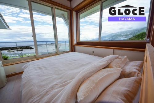 a large bed in a room with windows at GLOCE 葉山 Ocean View House 都心から1時間 湘南の絶景を独り占めペットok 出張BBQ有り in Yokosuka